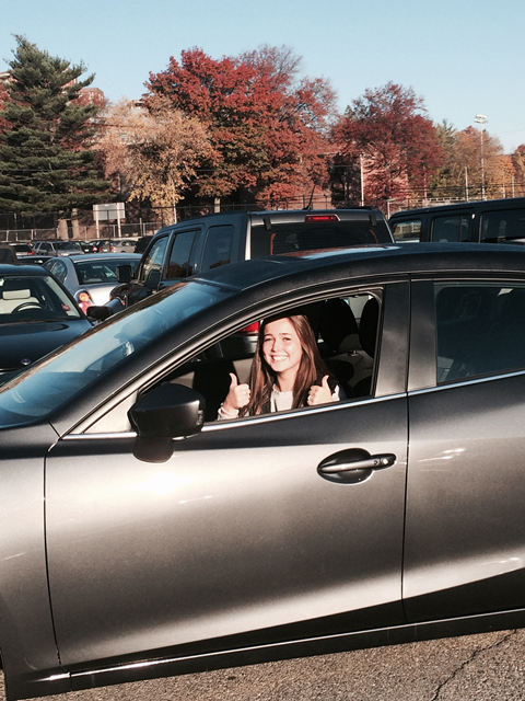 Senior+Kerry+Fahan+takes+both+hands+off+the+wheel+to+pose+for+a+picture+in+her+car.+She+is+a+proud+driving+school+graduate.+