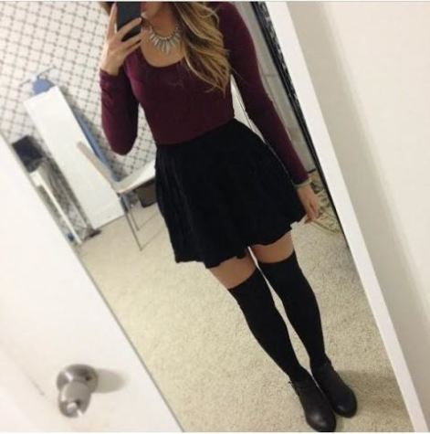 This young lady is wearing a maroon long sleeve crop top with a black skater skirt with high knee socks. 
